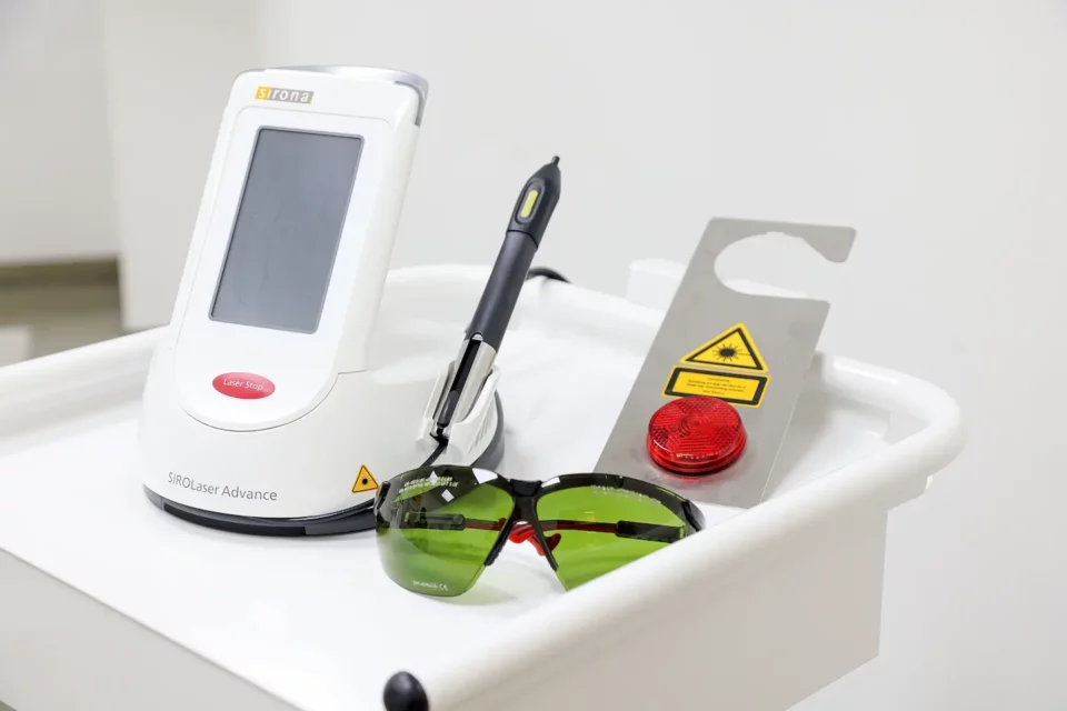 Lasergerät mit Schutzbrille und Warnschild für dentale Laserbehandlung.